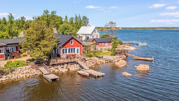 A lakeside property with docked boats, a wooden pier, and a red building.