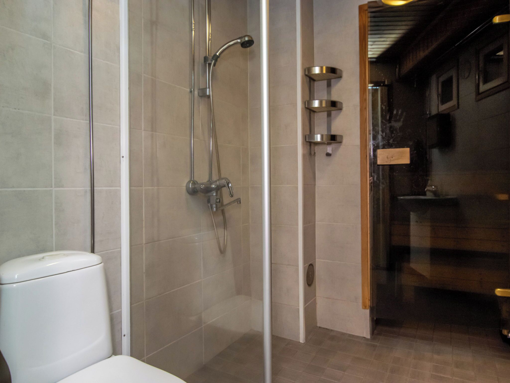 A bathroom with a glass-enclosed shower, a toilet, and a sink.