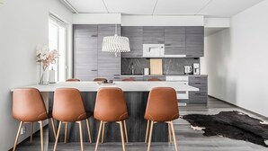 A modern kitchen with a central island, grey cabinets, and a hanging light fixture.