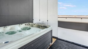 A hot tub on a balcony with a clear view of the sky and a distant landscape.