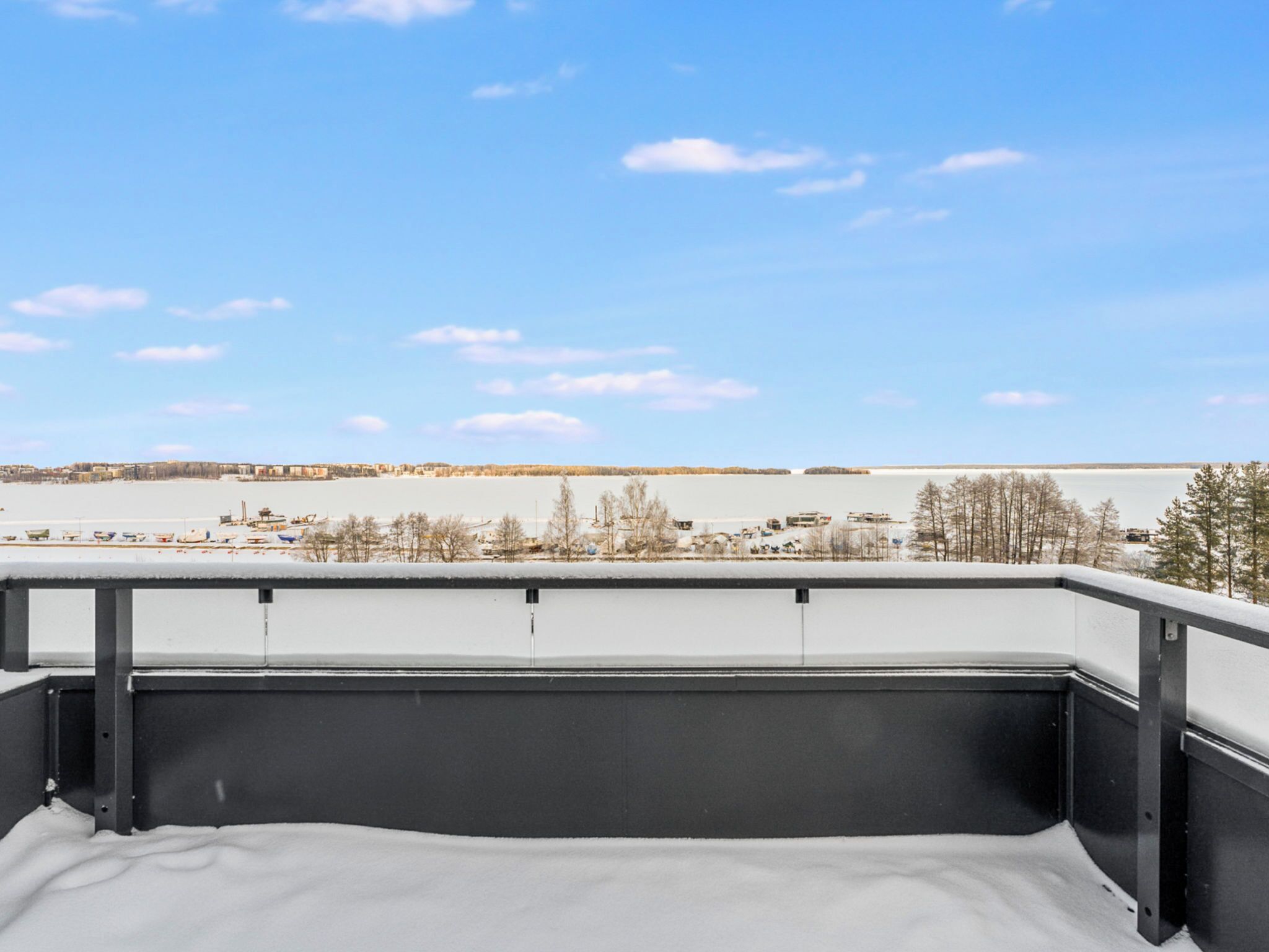 Ein Balkon mit Blick auf eine verschneite Landschaft und ein Gewässer.