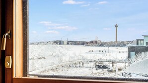 A window with a view of a snowy landscape, a tower, and industrial buildings.