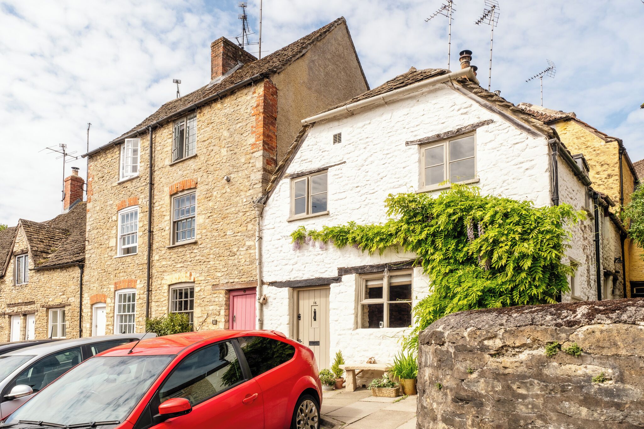 A row of traditional stone houses with a red car parked in front.
