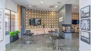 Eine moderne Küche mit geometrischer Spritzschutzwand, einem Flachbildfernseher und einem Essbereich mit Korbstühlen und einem zentralen Tisch.