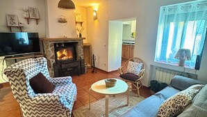 Ett vardagsrum med en öppen spis, en tv, en soffa och en matplats.