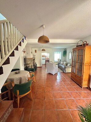 Un vaste espace de vie comprenant une table à manger, des chaises, un canapé, un meuble en bois et un escalier.