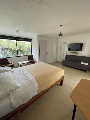 Ein Schlafzimmer mit Bett, Fernseher, Sofa und Kleiderschrank.