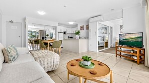 Eine moderne Wohnung mit Wohnzimmer, Essbereich, Küche und Fernseher.