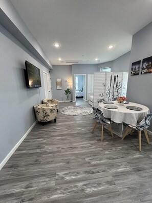 A modern dining area with a round table, chairs, and a television mounted on the wall. - Cozy 1-bedroom apartment in delightful Newark with AC (Newark)