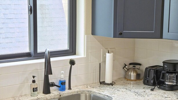 A kitchen with a double sink, a kettle, a toaster, and a coffee maker.