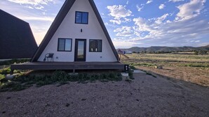 A triangular building with a door and windows, a chair outside, and a sign with the number 3.
