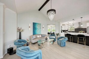 Ein modernes Wohnzimmer mit einer Couch, Sesseln, einem Couchtisch und einer Deckenleuchte.