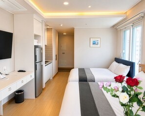 Habitación de hotel con cama, mesita de noche y una pequeña kitchenette.