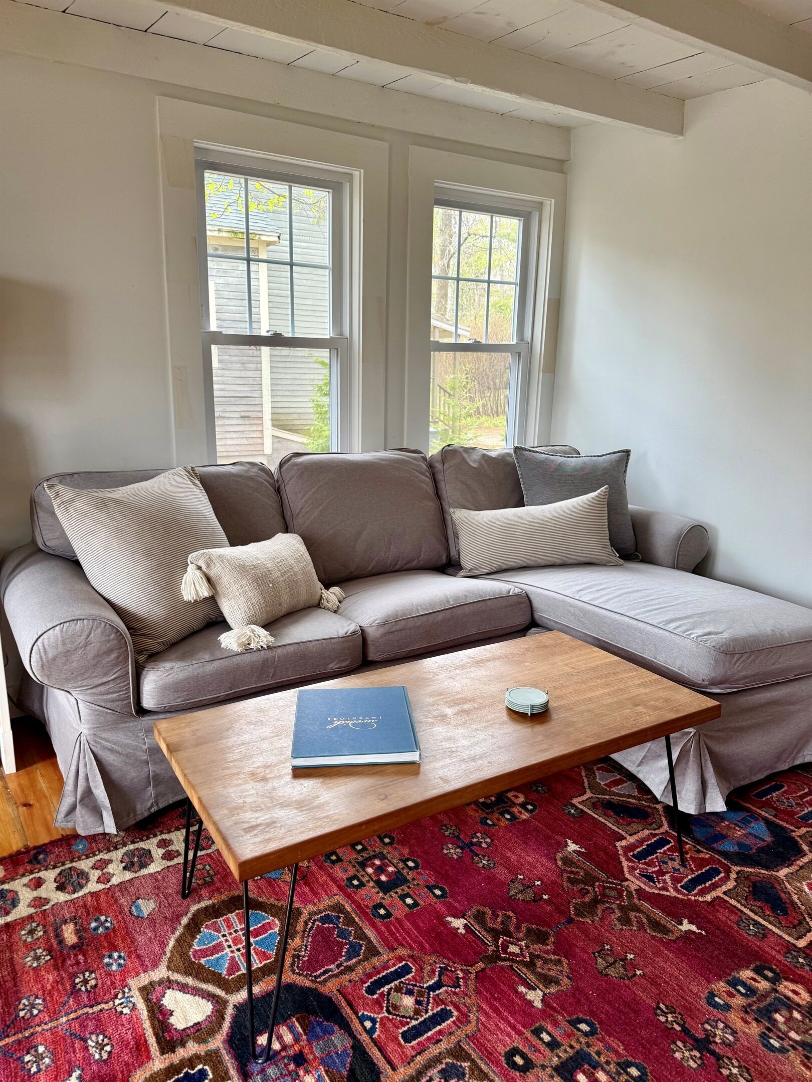 A modern living room with a grey sectional sofa, a wooden coffee table, and a patterned rug.