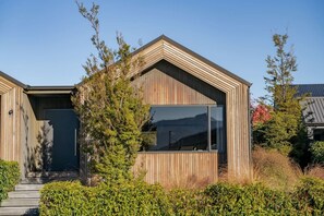 A modern wooden house with a large window and a garage door. - Whare Toi | Designer Stay with Mountain Views (Wānaka)