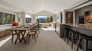 Una cucina moderna con isola centrale, zona pranzo con tavolo e sedie, e vista sull'esterno.
