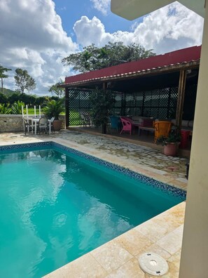 Una piscina al aire libre, sombrillas, sillones reclinables de piscina