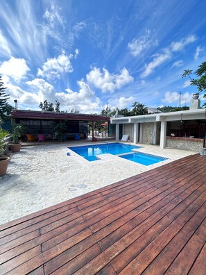 Una piscina al aire libre, sombrillas, sillones reclinables de piscina