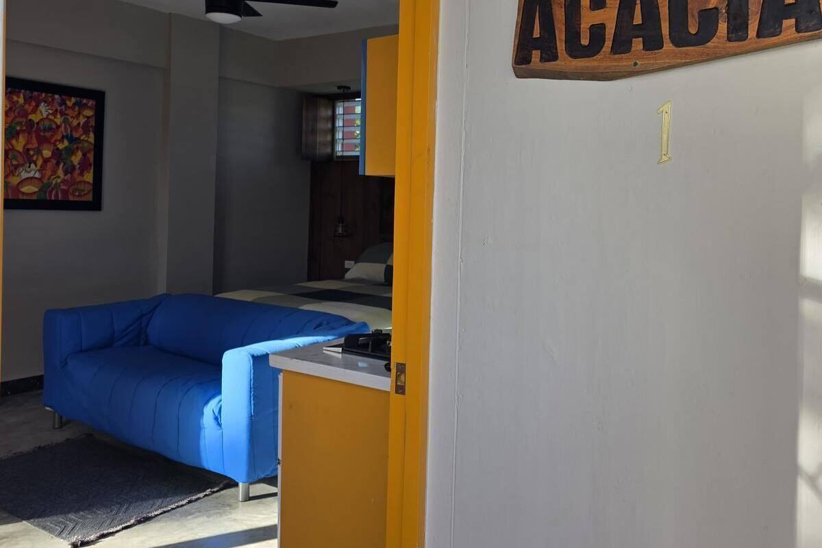 A room with a bed, a blue sofa, a ceiling fan, and a sign reading 'ACACIA'.