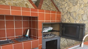 Una cocina con pared de piedra, horno empotrado y pileta.