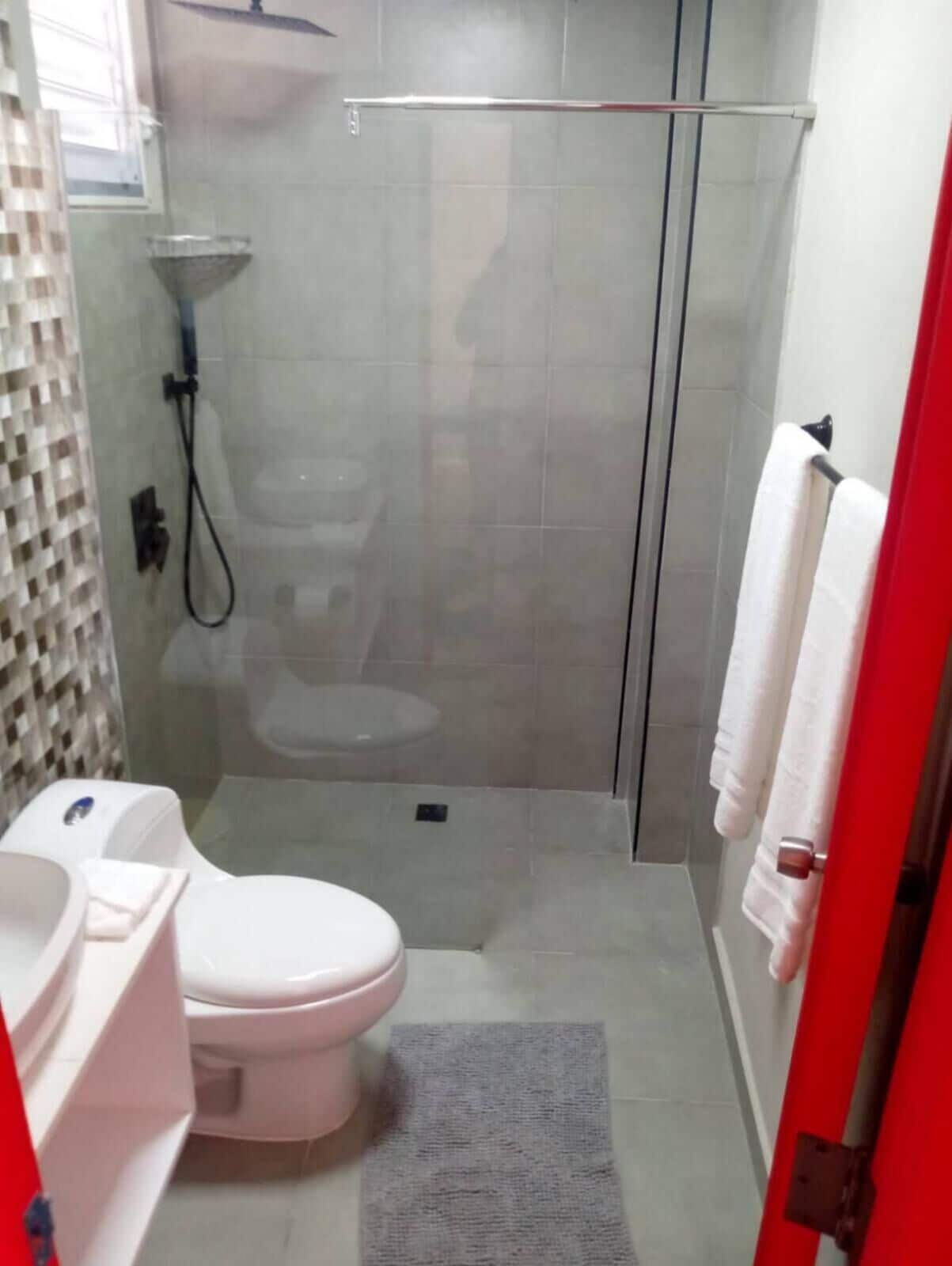 A bathroom with a shower, toilet, and sink.