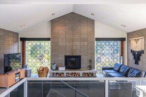 Una sala de estar moderna con chimenea, un sofá, un televisor y un balcón con vistas.