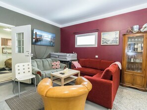 A living room with a sofa, armchair, and a television.