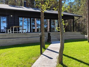 En träaltan som leder fram till en modern byggnad med stora fönster och en bänk.