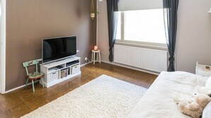 A bedroom with a bed, a TV, a small table, and a window with curtains. - Villa aurinkorinne by Interhome (Fiskars)