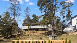 A modern house with a balcony, surrounded by a wooden deck and small trees. - Villa aurinkorinne by Interhome (Fiskars)