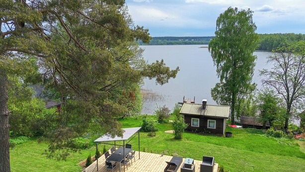 A lakeside property with a deck, outdoor seating, and a small house. - Villa aurinkorinne by Interhome (Fiskars)