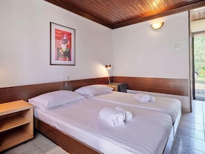 A hotel room with two beds, a wooden headboard, a framed picture on the wall, a bedside table, and a nightstand with a lamp. - Naturist Park Koversada Villas Vrsar (Vrsar)