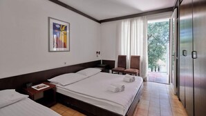 Habitación de hotel con una cama grande, un escritorio, dos sillas, un armario y un cuadro en la pared.