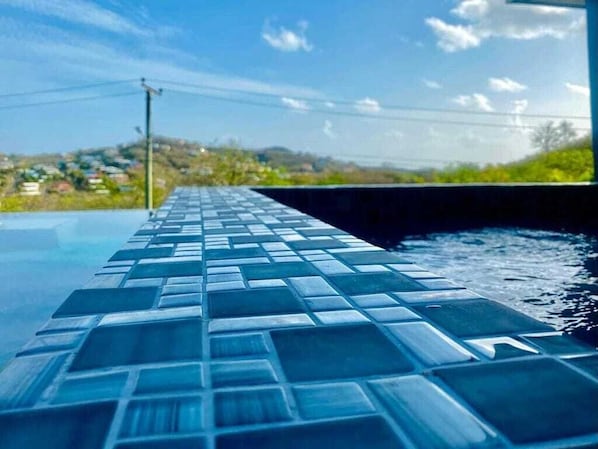 A swimming pool with a tiled edge and a view of a residential area in the background.