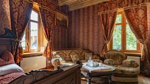 A room with a bed, two sofas, a coffee table, and a window with curtains. - Dwór Mysinek (Bobowo)