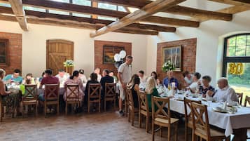A rustic dining area with wooden beams, brick walls, and a large window.