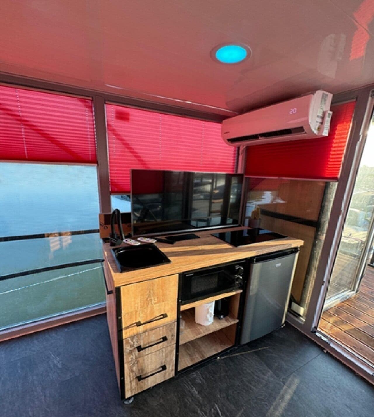 A compact kitchenette with a microwave, stove, and storage drawers.