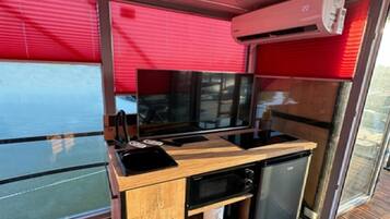 A compact kitchenette with a microwave, stove, and storage drawers.