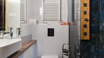 A modern bathroom with a white sink, a glass shower enclosure, and a marble wall.