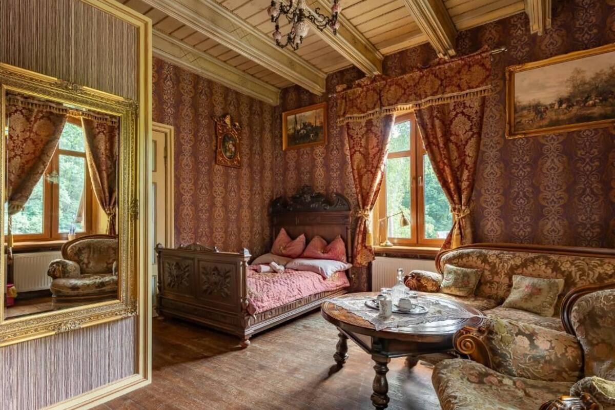 Una habitación con cama, sofá, mesa y espejo.