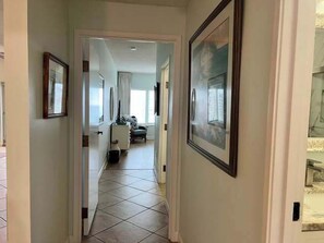 A hallway with framed pictures, a tiled floor, and a door leading to another room. - Spacious Coastal Escape for Family Getaways (Miramar Beach)