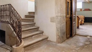 A staircase with a wrought iron railing leading to a room with a stone wall and a wooden door.