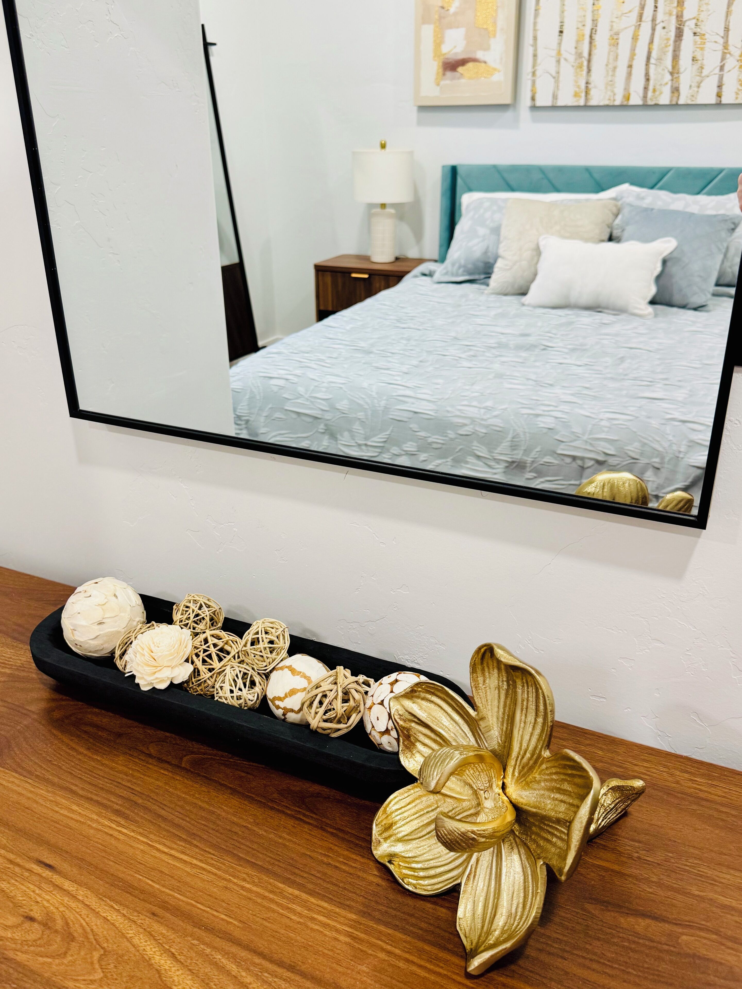 A bedroom with a bed, a nightstand, a lamp, and a decorative shelf with various items.