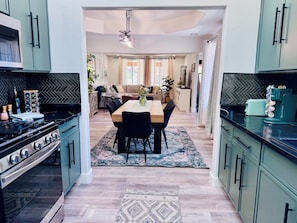 A modern kitchen with a dining area, a stove, and a coffee machine.