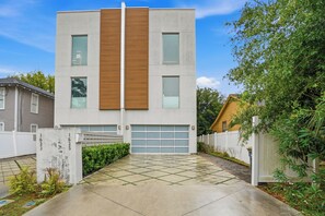 Ein modernes, zweistöckiges Gebäude mit Garage, Betonauffahrt und weißem Zaun.