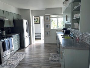A modern kitchen with stainless steel appliances, a built-in oven, and a large window providing natural light.