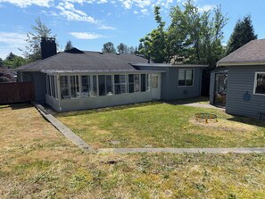 A residential house with a covered patio, a fenced yard, and a small garden area. - Cozy Lynn Valley Rancher Surrounded by Nature (North Vancouver)