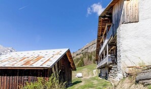 Ein rustikales Bergingerätehaus mit Metalldach, Holzfassade und Steinunterbau.