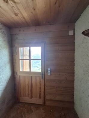 Eine Holztür mit Fenster, eine strukturierte Wand und eine kleine Steckdose.