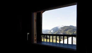Ein Fenster mit Blick auf eine gebirgige Landschaft.